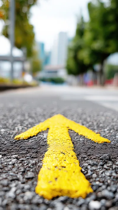 Yellow Painted Directional Arrow On Asphalt Road