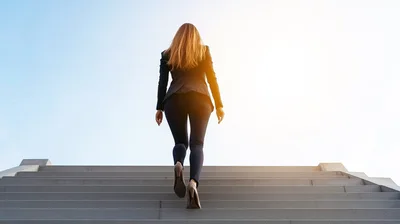 Businesswoman Walking Up Concrete Stairs Towards Bright Light