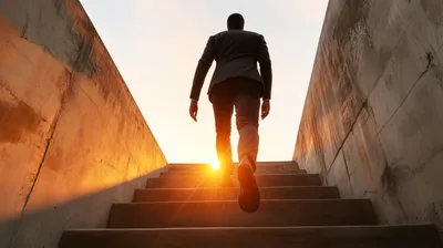Businessman Walking Up Concrete Stairs Towards Bright Sunlight