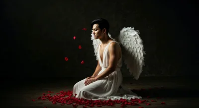 Young Asian Man Dressed As Angel Kneeling With Rose Petals