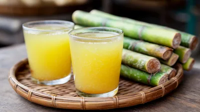 Two Glasses Of Fresh Sugarcane Juice On A Woven Tray