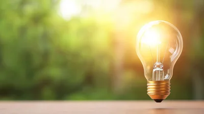 Glowing Light Bulb Floating Above Wooden Surface