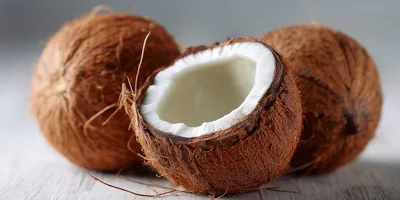 Three Whole And Halved Coconuts On White Surface