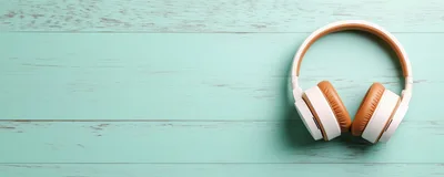 White Wireless Headphones On A Light Blue Wooden Surface