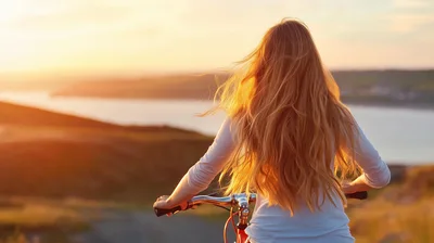 Woman Riding Bicycle At Sunset Overlooking The Sea