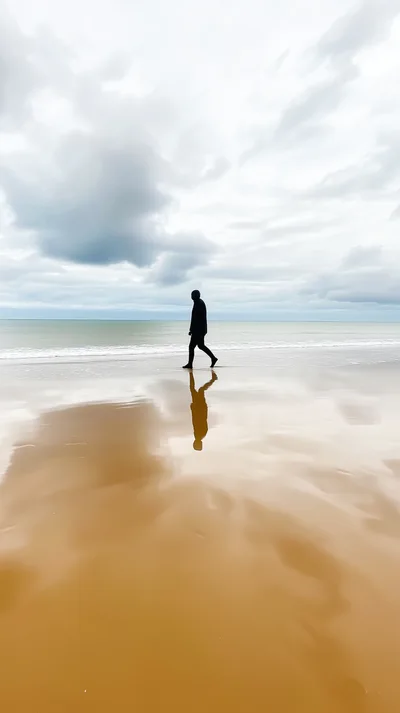 Silhouette Of A Person Walking On A Sandy Beach