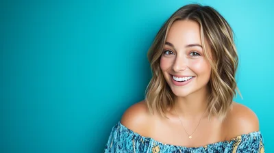 Smiling Young Woman With Blonde Highlights Against Teal Background