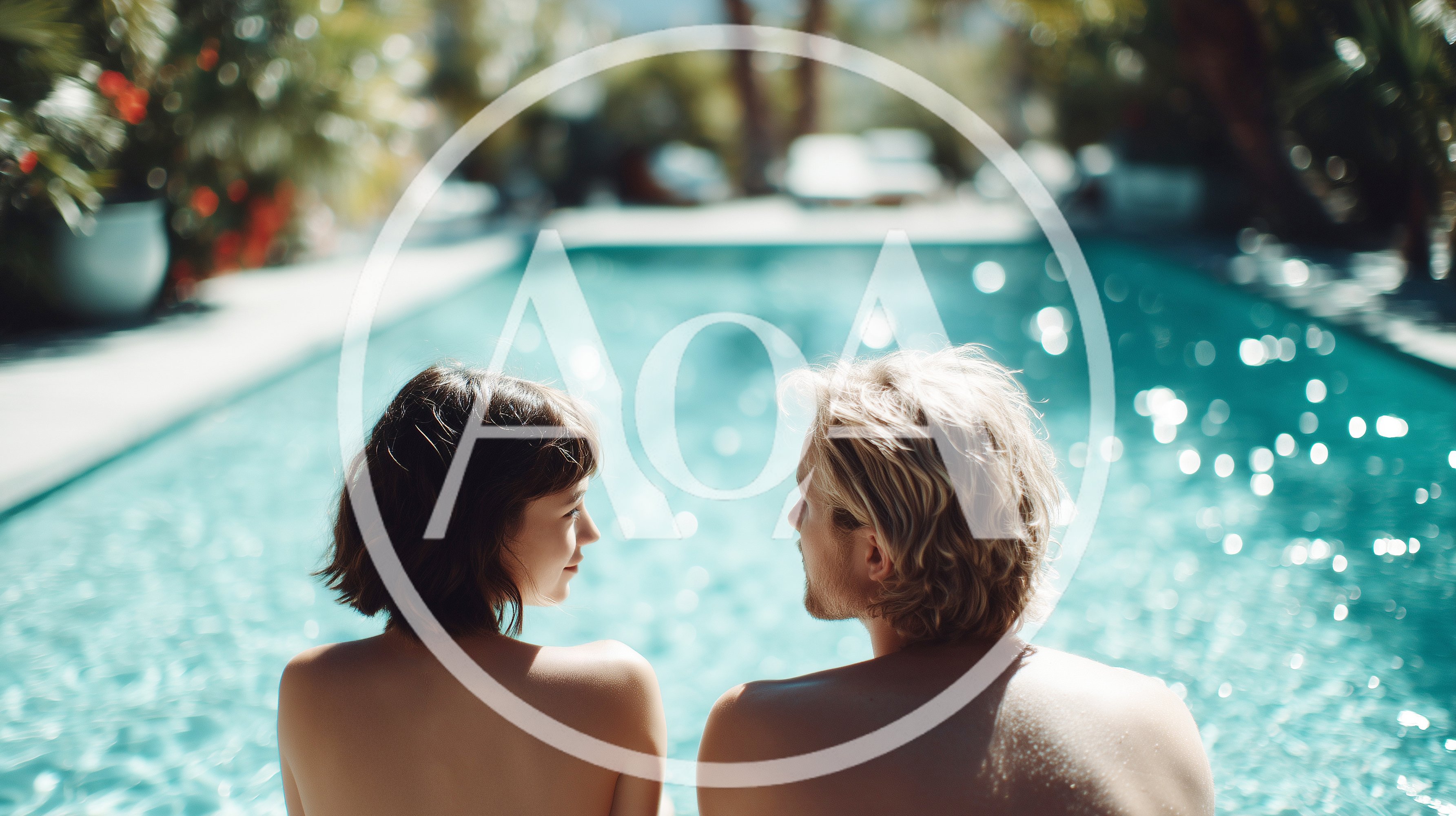 Young Couple Sitting Together By A Sunny Swimming Pool