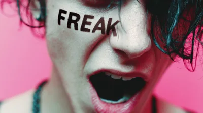 Close Up Of A Person Screaming With Freak Written On Face