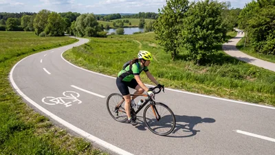 Female Cyclist Riding Road Bike On Scenic Path