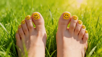 Feet With Smiley Face Nail Art In Green Grass