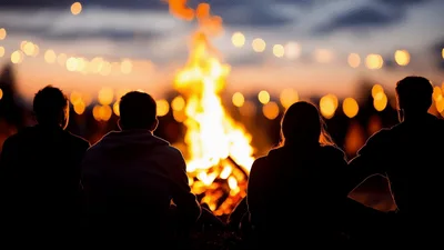 Friends Sitting Around A Campfire At Sunset