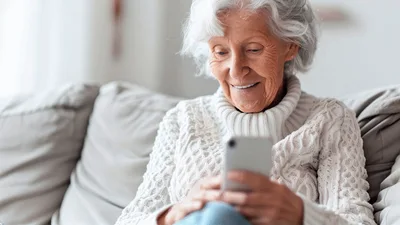 Senior Woman Using Smartphone While Sitting On Sofa