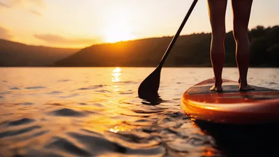 Person Paddleboarding On A Lake At Sunset
