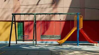 Empty Playground Swings and Slides Against Colorful Wall