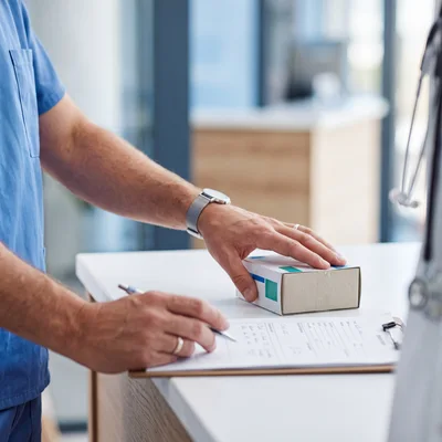 Healthcare Professional Writing Prescription Details On Clipboard