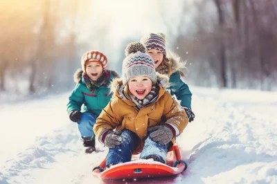 Three Happy Children Sledding Down A Snowy Hill