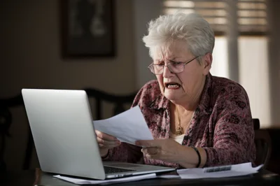 Senior Woman Looking Concerned While Reviewing Financial Documents