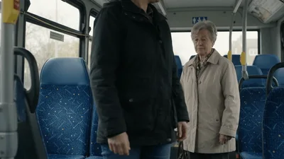 Woman Standing Up From Bus Seat Next To Senior