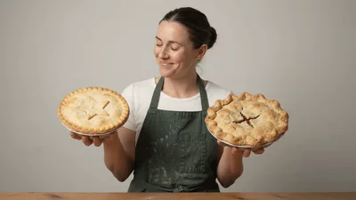 Baker Holding Two Different Homemade Fruit Pies