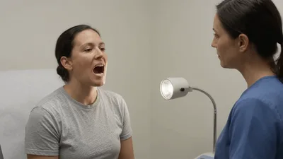 Doctor Examining Patient Throat In Medical Office
