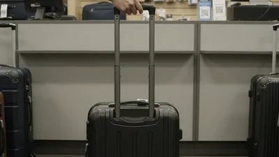 Hand Adjusting Telescopic Handle On Black Rolling Suitcase