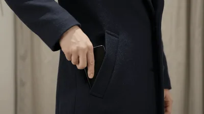 Person Placing Smartphone Into Dark Wool Coat Pocket