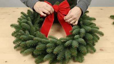 Person Removing Red Velvet Bow From Christmas Wreath