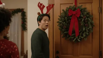 Young Man Wearing Reindeer Antlers Laughing At Holiday Party