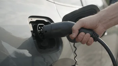 Hand Unplugging Electric Vehicle Charging Cable From Port