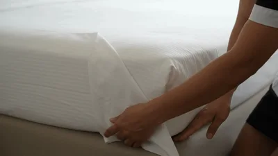 Hotel Housekeeper Tucking In White Bed Sheet