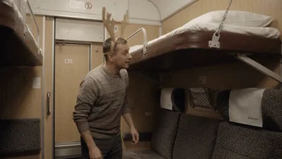 Man Wearing Reindeer Antlers Entering Train Compartment