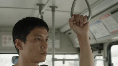 Asian Man Holding Bus Handle While Commuting