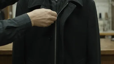 Tailor Zipping Up A Black Wool Coat