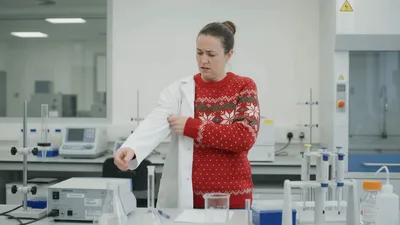 Female Scientist Putting On A White Lab Coat