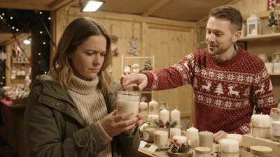 Woman Smelling Scented Candle At Christmas Market Stall