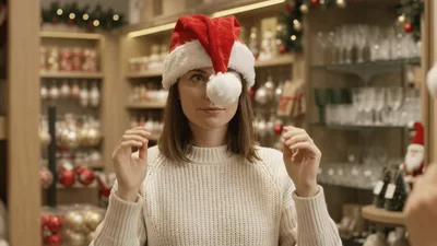 Woman Trying On Santa Hat In Christmas Store