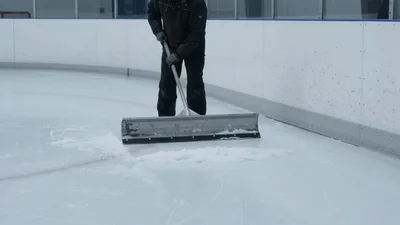 Ice Rink Worker Clearing Snow With A Large Scraper