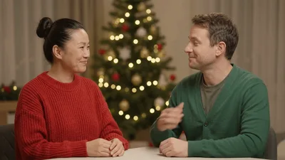 Couple Playing Rock Paper Scissors In Front Of Christmas Tree