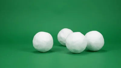 Four White Snowballs Rolling On Green Background