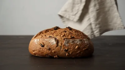 Hand Removing Linen Cloth From Freshly Baked Bread