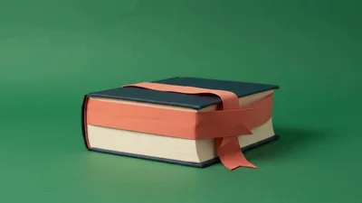 Gift Wrapped Book With Pink Ribbon On Green Background
