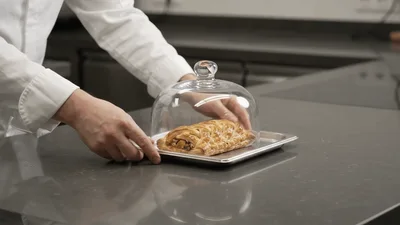 Chef Placing Glass Cloche Over Baked Pastry