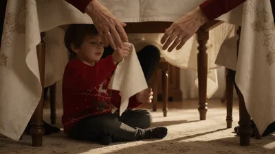 Little Boy Playing Under Dining Table During Christmas Dinner