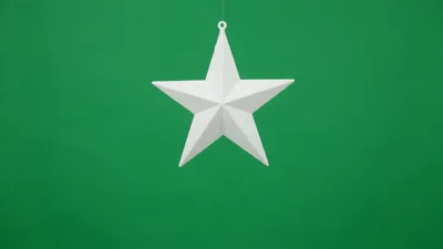 White Christmas Star Ornament Hanging Against Green Background