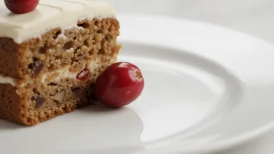 Fresh Cranberry Rolling Onto A White Plate Beside Cake
