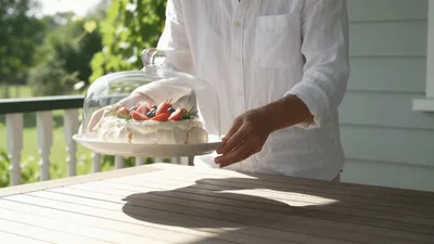Person Placing Pavlova Dessert On Outdoor Wooden Table