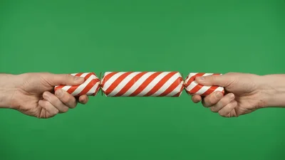 Two Hands Pulling Apart A Red And White Christmas Cracker