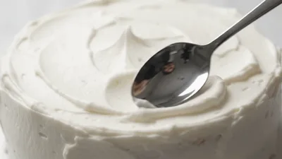 Spoon Creating Swirls On White Frosted Cake