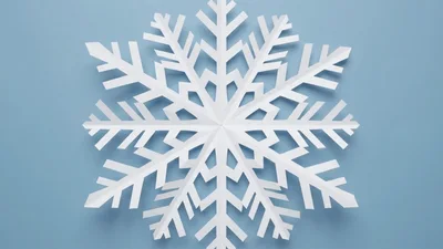 White Paper Snowflake Zooming In On Blue Background
